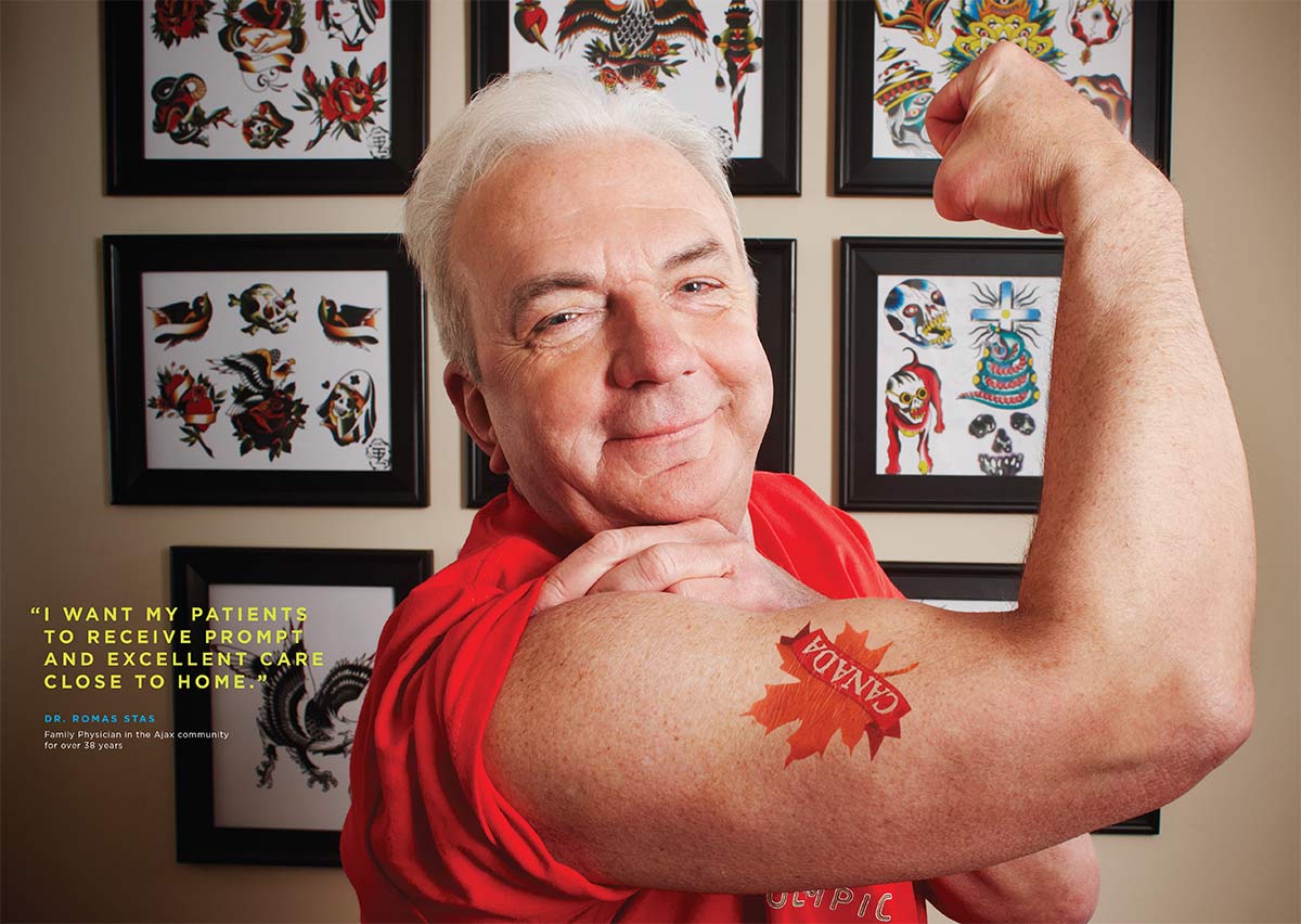 Smiling doctor showing arm muscle with a Canada maple leaf tattoo on his bicep