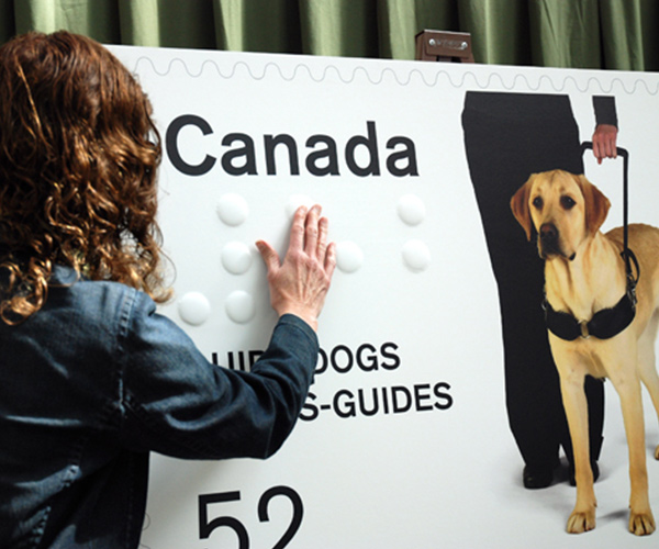 Guide Dogs giant stamp and person touching the braille